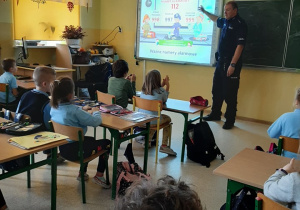 Policjant prezentuje zasady ruchu drogowego na tablicy interaktywnej