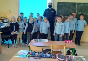 Policjant wraz z uczniami pozują do zdjęcia