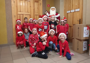 Uczniowie klasy 0 pozują do zdjęcia w mikołajkowych czapkach