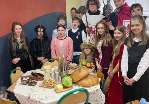 "Królewska uczta" - uczniowie w strojach dworzan i królów pozują do zdjęcia nad zastawionym stołem.