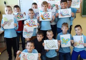 Uczniowie prezentują prace plastyczne wykonane metodą kropki.