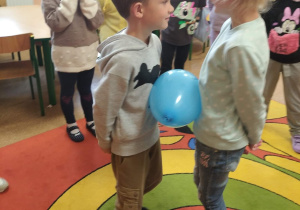 Dzieci uczestniczą w zabawie z balonem.