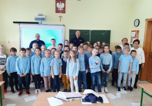 Uczniowie klas III pozują do zdjęcia z policjantami.