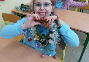 Uczennica prezentuje wykonany przez siebie stroik świąteczny.