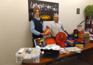 Dyrektor wraz z Przewodniczącym Samorządu Uczniowskiego prezentują zakupione pomoce dydaktyczne.