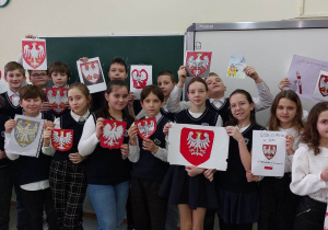 Uczniowie prezentują wykonane przez siebie godła.
