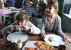 Dzieci jedzą wykonane przez siebie pizze.