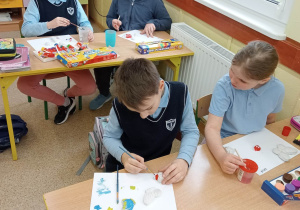 Uczniowie ozdabiają wykonane przez siebie odlewy z gipsu.