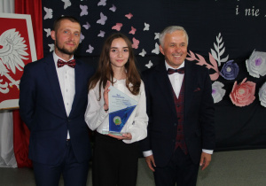 Dyrektorzy pozują do zdjęcia z najlepszym absolwentem szkoły.