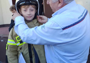 Uczeń przymierza strój strażacki.