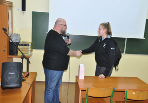 Uczennica otrzymuje gratulacje od prowadzącego.