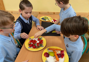 Uczniowie przygotowują pracę plastyczno - techniczną z owoców i warzyw.