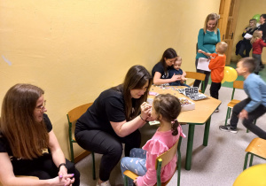 Nauczyciel maluje buźki przybyłym dzieciom.
