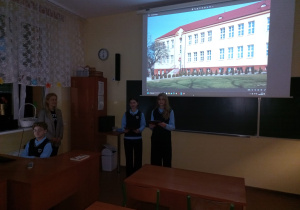 Nauczyciel wraz uczniami prezentuje historię szkoły.