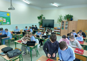 Uczniowie sterują robotami.