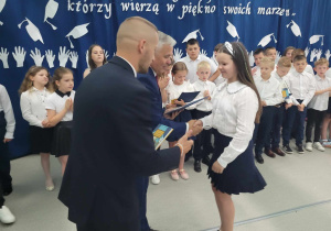 Dyrektorzy wręczają uczennicy nagrodę.