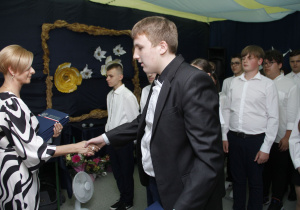 Wychowawca wręcza świadectwa uczniom klasy ósmej.