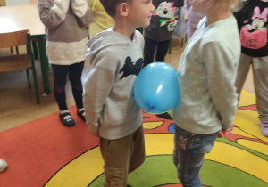 Dzieci uczestniczą w zabawie z balonem.