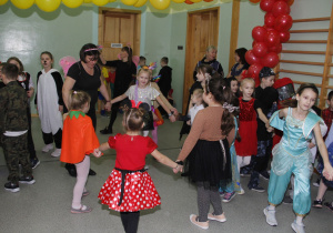 Dzieci wraz z wychowawcą tańczą w kółeczku.